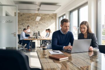 Steuerberater und Fachkraft prüfen digitale Belege und Buchungsdaten am Laptop in moderner Kanzlei mit On-Premise-Software von microdat.